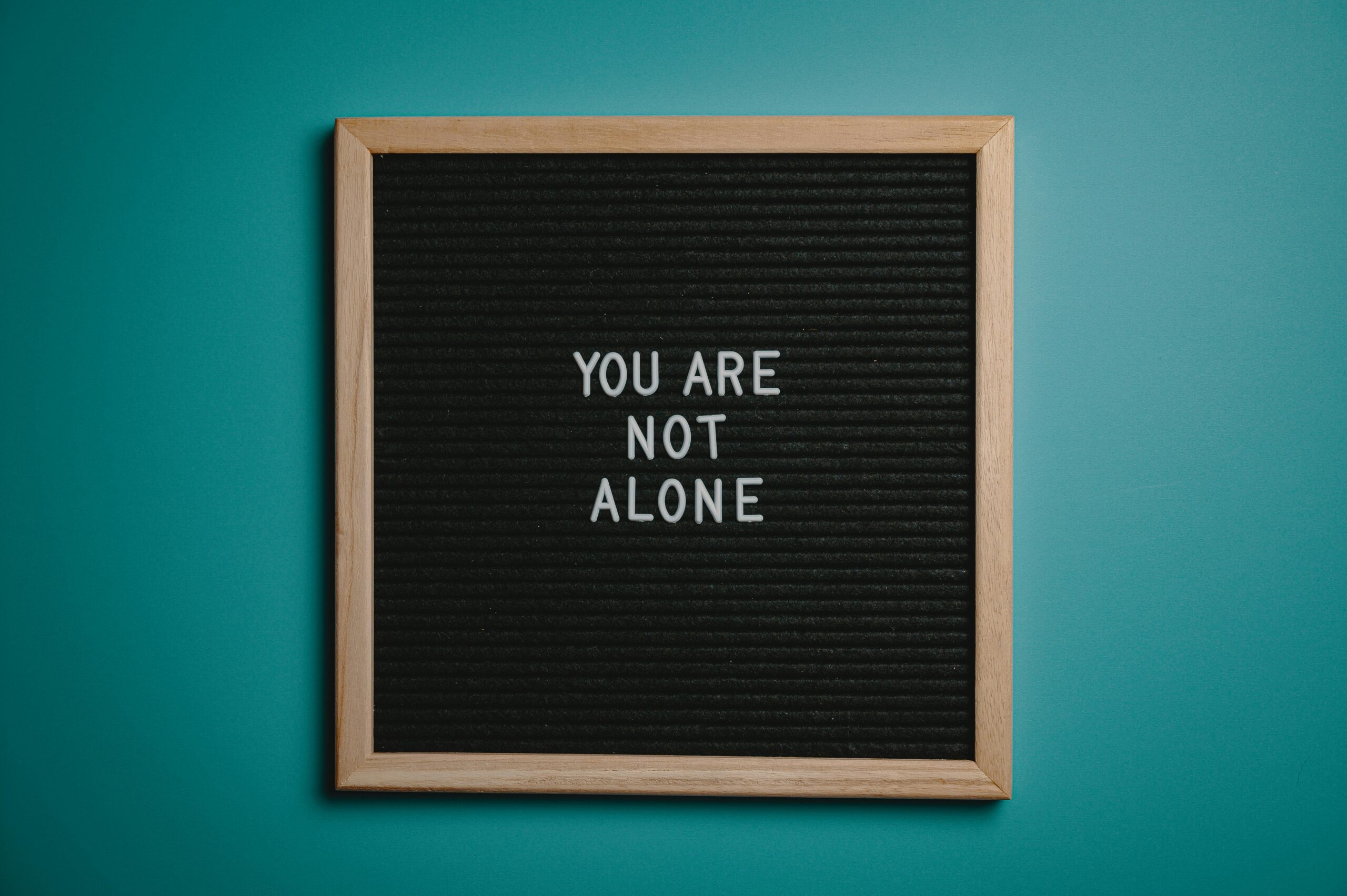 A wooden letter board displays a motivational message against a teal background.